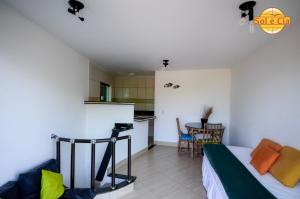 a bedroom with a bed and a kitchen with a table at Pousada Sol e Cia Tur in Caraguatatuba