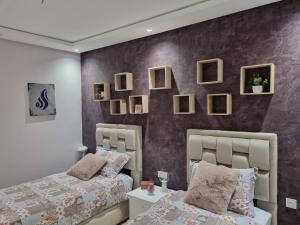 a bedroom with two beds and pictures on the wall at Vue panoramique sur la baie de Tanger in Tangier