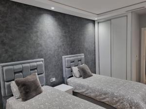 a bedroom with two beds in front of a wall at Vue panoramique sur la baie de Tanger in Tangier