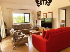 a living room with a red couch and a tv at Magia da Serra Casa Temporada in Pirenópolis