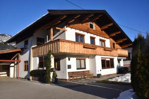 een wit huis met een houten dak bij Apartment Lopez in Sankt Johann in Tirol