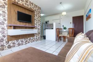 een woonkamer met een bank en een tv aan de muur bij Residencial Califórnia em Lagoa Nova por Carpediem in Natal
