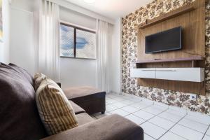 een woonkamer met een bank en een tv aan de muur bij Residencial Califórnia em Lagoa Nova por Carpediem in Natal
