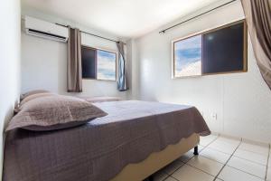 a bedroom with a bed and two windows at Residencial Califórnia em Lagoa Nova por Carpediem in Natal