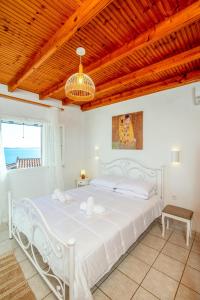 Cama blanca en habitación con techo de madera en Aphrodite's maisonette on Corfu island en Barbati