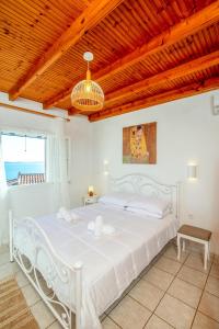 a white bed in a room with a wooden ceiling at Aphrodite's maisonette on Corfu island in Barbati