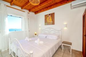 a white bedroom with a white bed and a window at Aphrodite's maisonette on Corfu island in Barbati
