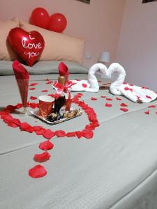 Un letto con cuori rossi sopra con un vassoio di cibo e un cuore d'amore di B&B Petra Hercules a Torre Annunziata
