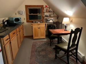 Cozy Tiny Haus Apt في Torrington: مطبخ صغير مع طاولة ومكتب مع تلفزيون