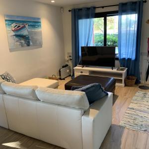 sala de estar con sofá blanco y TV en Stylish Beach House 600m to sea, en Cubelles
