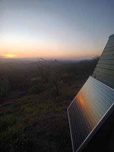 a solar panel on the side of a building with the sunset in the background at Sustainable, Off-Grid and Organic Cabins on a Farm in a Secluded Cloud Forest, Ultra Low Carbon Footprint in Puntarenas