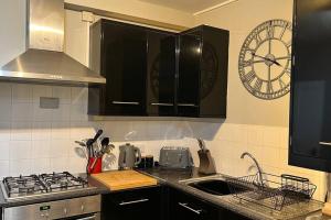 una cocina con fregadero y un reloj en la pared en Pavilion View, en Buxton