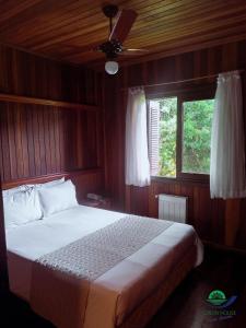 a bedroom with a bed in a wooden room at Morada Das Araucárias in São Francisco de Paula