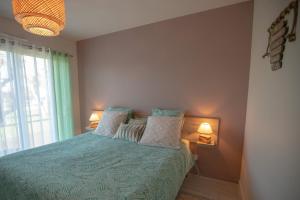um quarto com uma cama com almofadas e 2 candeeiros em Maison à 800m de la plage em Saint-Lunaire