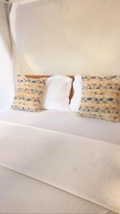 Una cama con sábanas blancas y almohadas. en Upper Hill Place en Dar es Salaam