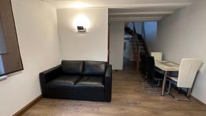 a living room with a black leather couch and a table at Ferienwohnung zum Winterberg in Elsterwerda +9 photos