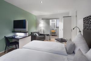 Schlafzimmer mit einem Bett und einem Schreibtisch mit einem TV in der Unterkunft Wirtshaus & Hotel Goldener Greif in Edelsfeld