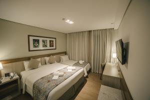 a hotel room with two beds and a television at Interludium Iguassu Hotel by Atlantica in Foz do Iguaçu