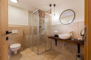 een badkamer met een douche, een toilet en een wastafel bij Collis Hill in Kals am Großglockner