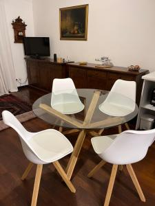 une table en verre et quatre chaises blanches dans une pièce dans l'établissement Golfo Dei Poeti Apartment, à Lerici