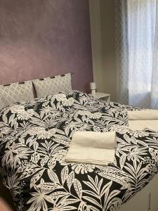 uma cama grande com um cobertor preto e branco em Casa Mirabello em Peveragno