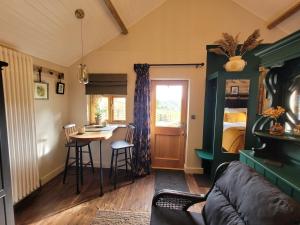 a living room with a couch and a table and a bed at Kettle Tree Cabin in Welshpool
