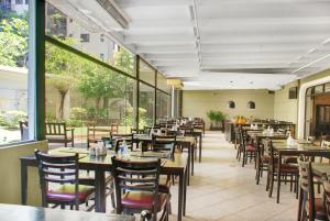 a restaurant with wooden tables and chairs and windows at Hotel com piscina e academia na Gomes de Carvalho in Sao Paulo