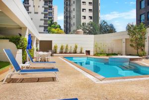 a swimming pool with two chairs and a table at Hotel com piscina e academia na Gomes de Carvalho in Sao Paulo