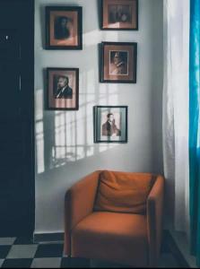 uma sala de estar com uma cadeira e quadros na parede em Hostal Mi Rincón em Santo Domingo