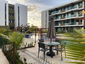 a table with an umbrella and chairs next to a building at Mana Beach Experience - Muro Alto - Flat Luxo 2 qtos in Porto De Galinhas