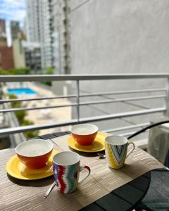 zwei Tassen und Teller auf einem Tisch auf einem Balkon in der Unterkunft Palermo Tessa I Appartment in Buenos Aires