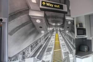 an airport hallway with a way out sign and escalators at Quaint Studio Flat in the Heart of London in London
