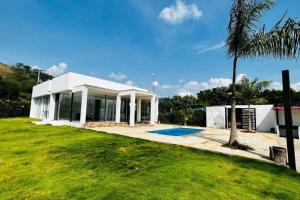 a white house with a palm tree next to a yard at ¡Quinta al Cielo! in Girardot