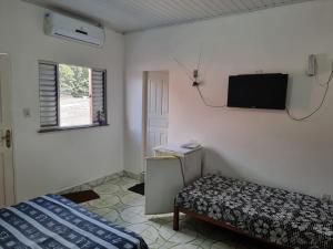ein Schlafzimmer mit einem Bett und einem TV an der Wand in der Unterkunft Suítes em Parintins in Parintins