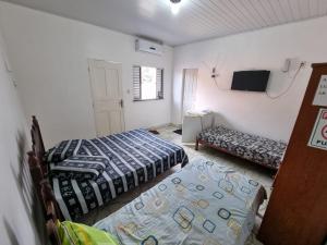 a room with two beds and a television in it at Suítes em Parintins in Parintins