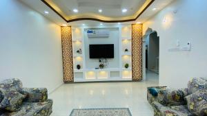 a living room with two chairs and a tv on a wall at .Alshorfa _ House. in Qurayyah