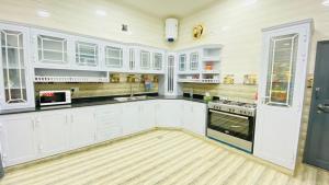 a kitchen with white cabinets and a wooden floor at .Alshorfa _ House. in Qurayyah