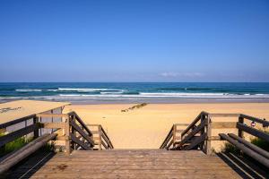 a wooden boardwalk leading to a beach with the ocean at T2 Mimizan plage in Mimizan