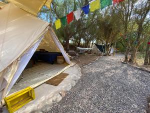 uma tenda com uma mesa, uma cadeira e árvores em CaminAndes Hostal em San Pedro de Atacama