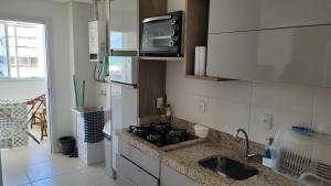 una pequeña cocina con fregadero y microondas en Praia Grande (13) - 2 quartos - 1 quadra Mar, en Torres