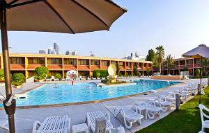 a pool at a hotel with chairs and an umbrella at Lou'lou'a Beach Resort Sharjah in Sharjah