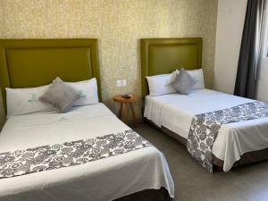 two beds in a hotel room withacersacers at Hotel Suites Regina in Veracruz