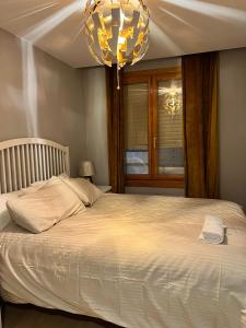 - une chambre avec un grand lit blanc et un lustre dans l'établissement Apartamento Zaragoza Centro, à Saragosse