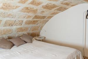 アルゲーロにあるLa Casina Apartmentのレンガの壁のベッドルーム1室(白いベッド1台付)