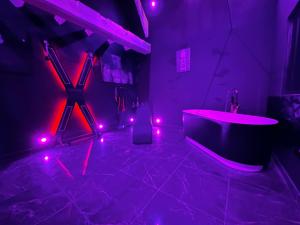 une salle de bains pourpre avec une baignoire et des lumières roses dans l'établissement Loveroom de luxe - Thème 50 nuances de grey maison privative spa insolite, à Douchy-les-Mines