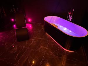 een zwarte badkamer met een bad met paarse verlichting bij Loveroom de luxe - Thème 50 nuances de grey maison privative spa insolite in Douchy-les-Mines