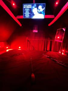 een donkere kamer met een tv en rode verlichting bij Loveroom de luxe - Thème 50 nuances de grey maison privative spa insolite in Douchy-les-Mines