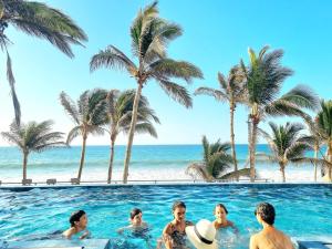 a group of people in a swimming pool next to the beach at Condominio, Las Pocitas de Máncora- Deluxe in Máncora