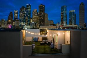 un balcón en la azotea con vistas a la ciudad por la noche en Lavish Downtown Home with Stunning Rooftop Deck Views, en Houston