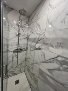 La salle de bains est pourvue d'une douche et de carrelage en marbre. dans l'établissement Apartamento Zaragoza Centro, à Saragosse